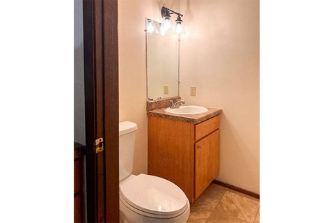 A bathroom with a toilet, sink, and mirror.