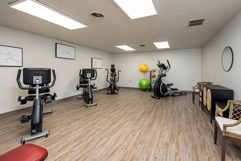 A gym room with exercise equipment and a bench.