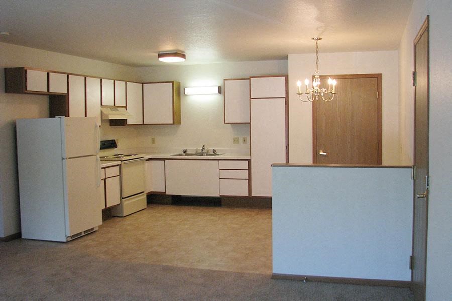 an empty kitchen with white appliances and white cabinets