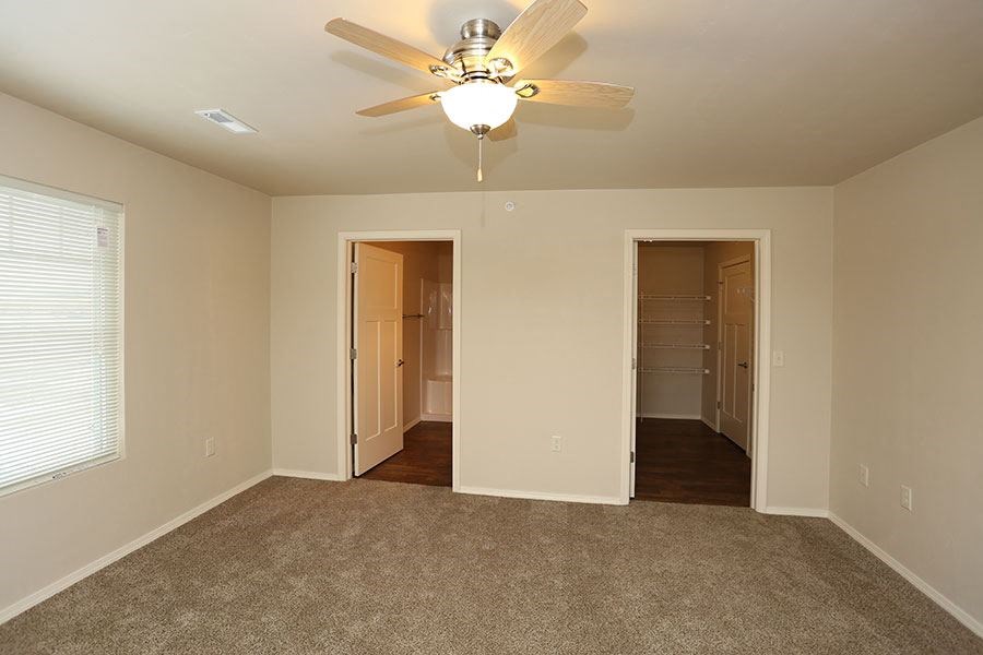 an empty living room with a ceiling fan