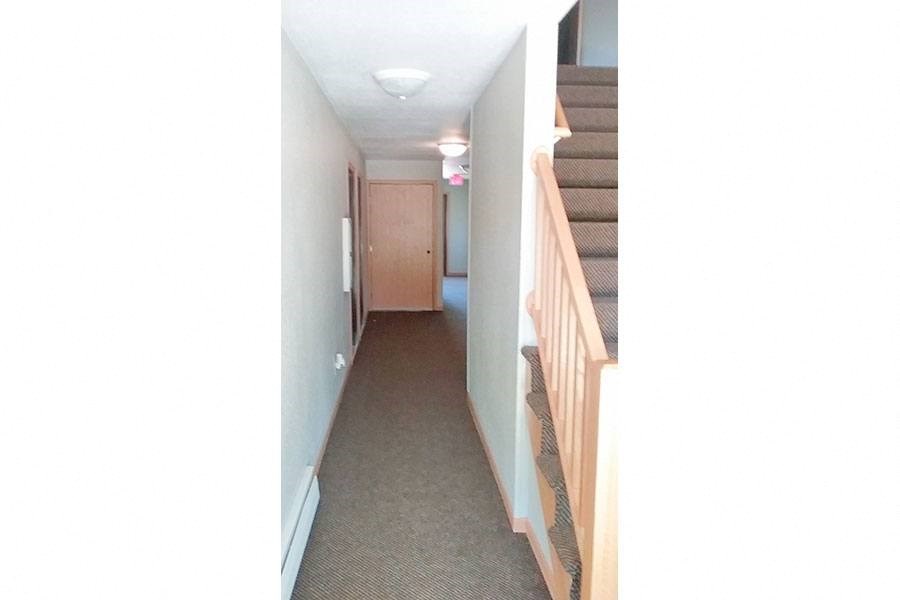 a long hallway with stairs and a hallway with a door