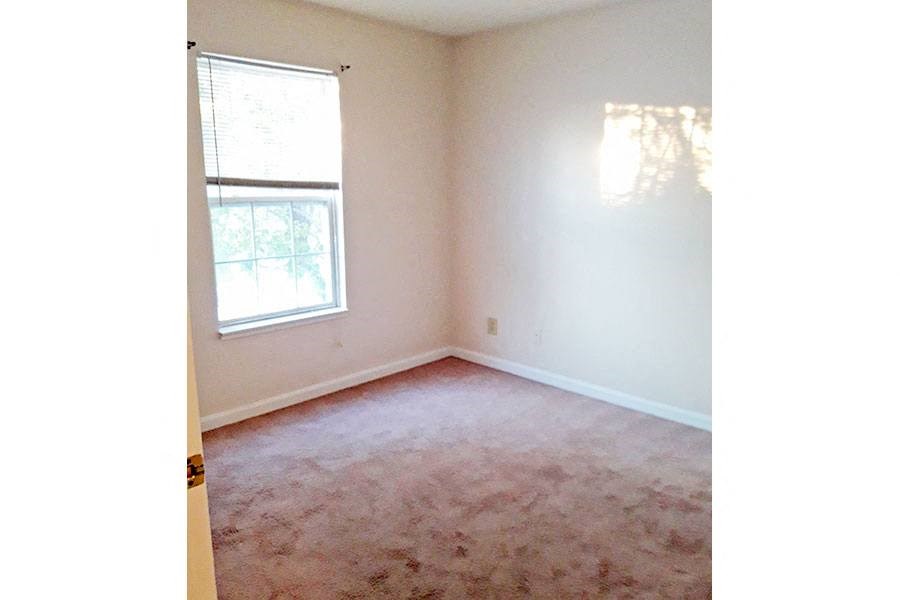 an empty room with a window and carpet