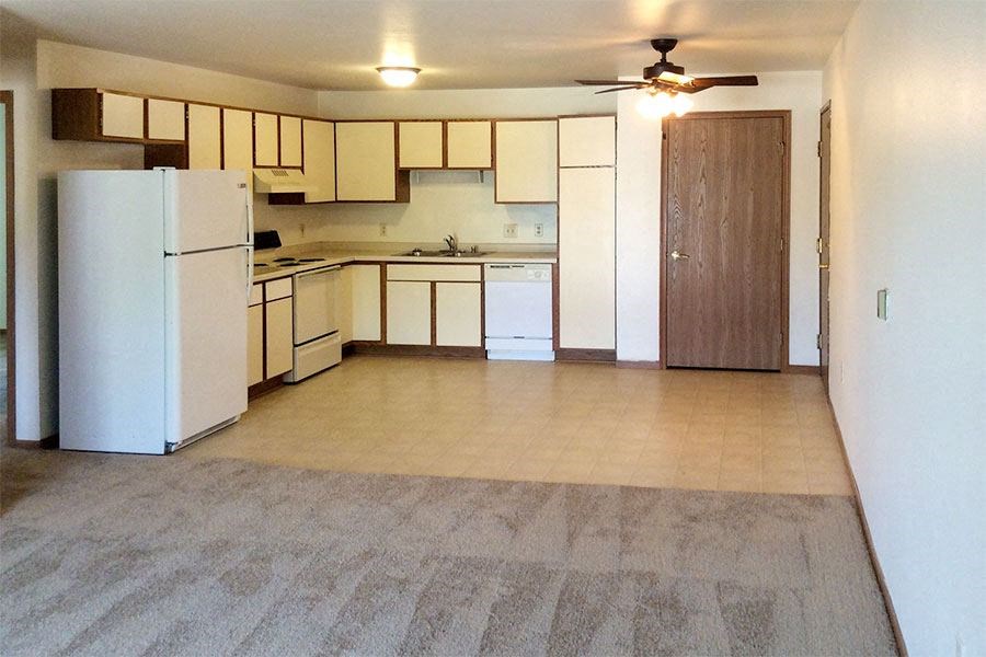 an empty kitchen with white appliances and a ceiling fan