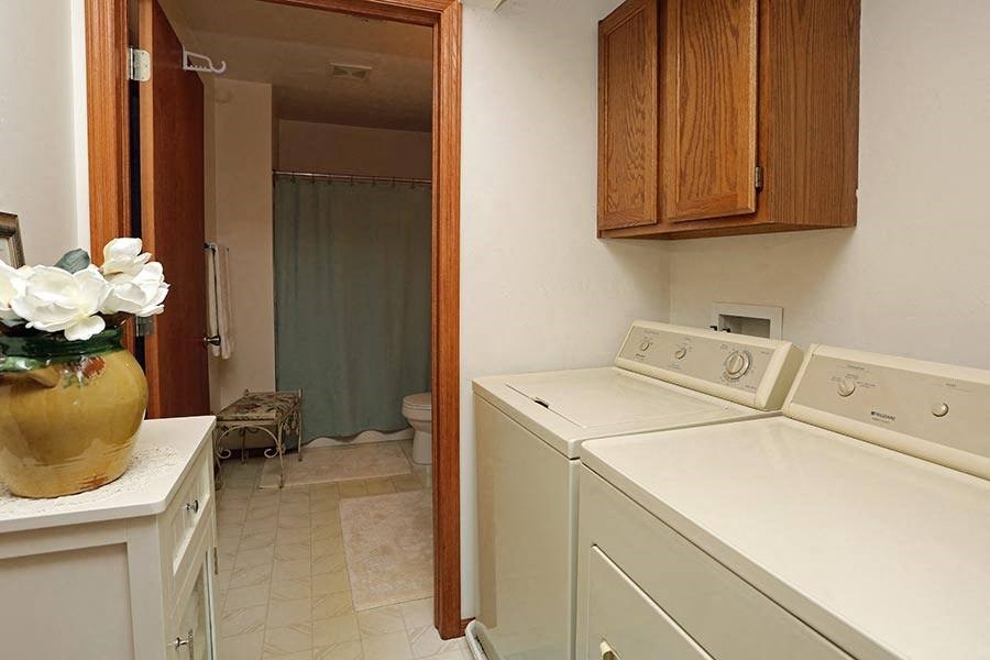 a laundry room with a washing machine and a vase of flowers
