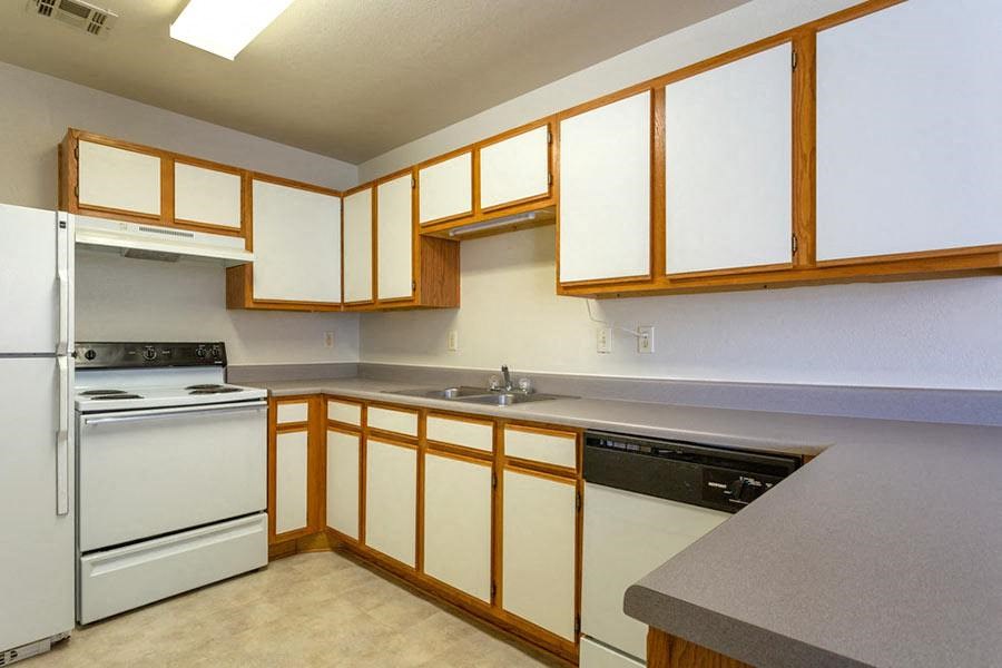 an empty kitchen with white appliances and wooden cabinets