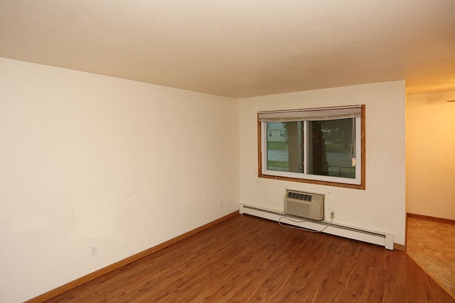 an empty room with a window and a wooden floor