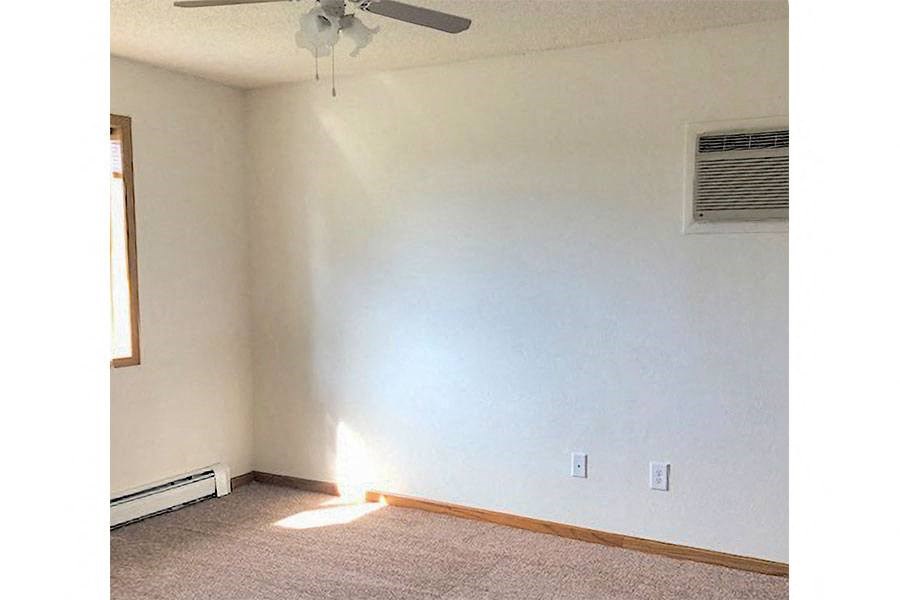 an empty room with a white wall and a ceiling fan