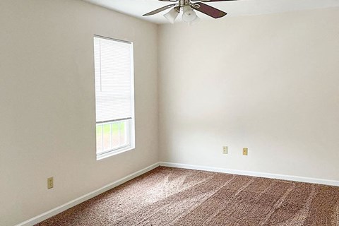 an empty room with a ceiling fan and a window