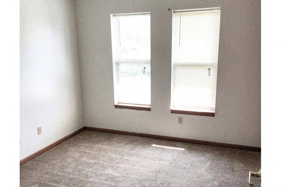 an empty room with two windows in it