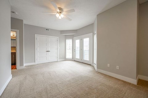 A spacious room with a ceiling fan and carpeted floor.