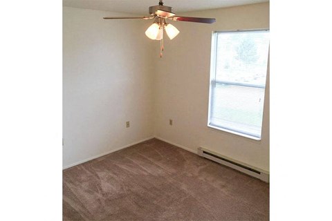 an empty bedroom with a ceiling fan and a window