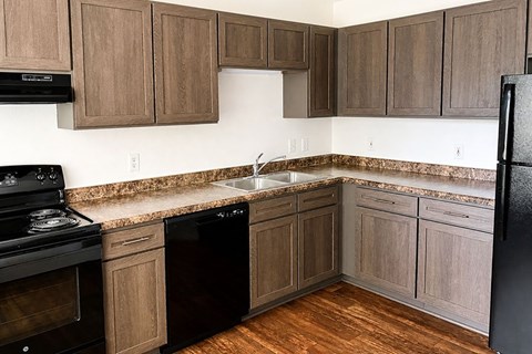 A kitchen with wooden cabinets and black appliances.