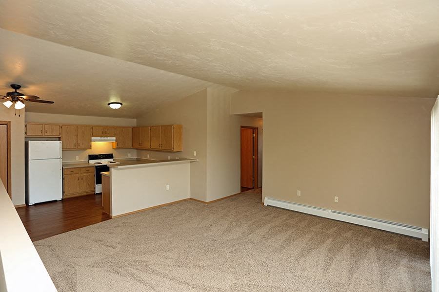 an empty living room and kitchen with a white refrigerator