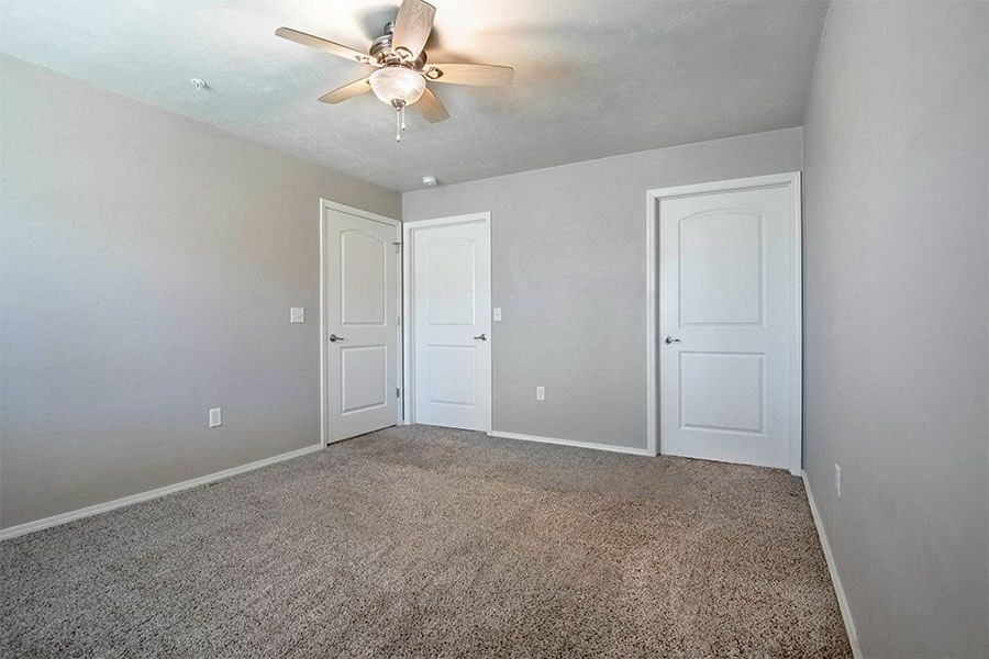 an empty room with two doors and a ceiling fan