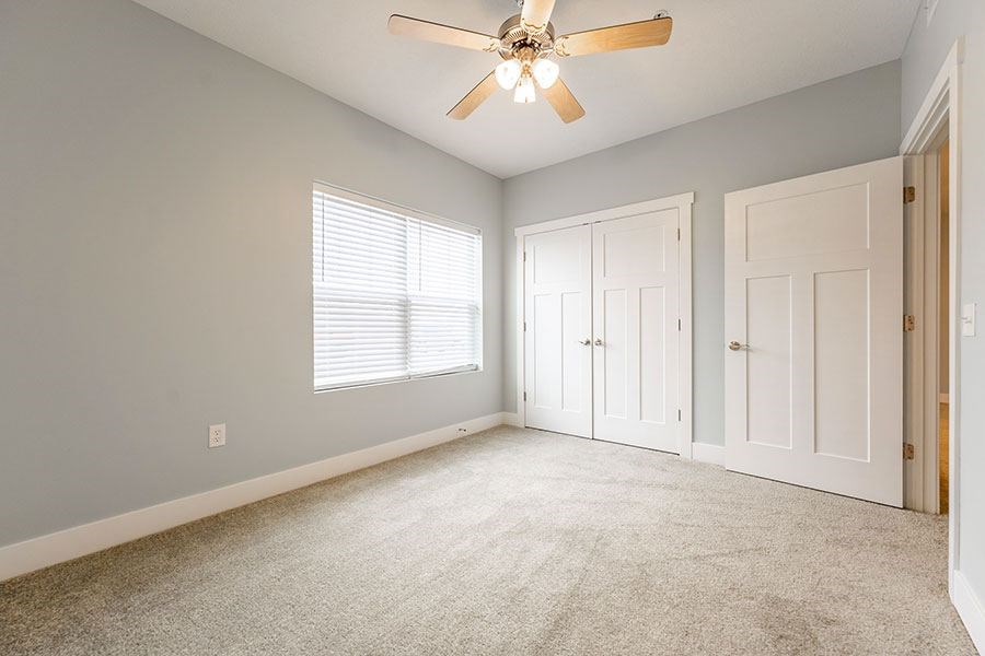 A room with a ceiling fan and carpeted floor.