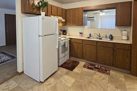 A white refrigerator in a kitchen with wooden cabinets.