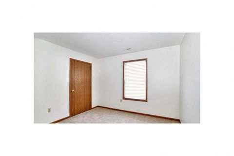 A room with a brown door and a window with blinds.