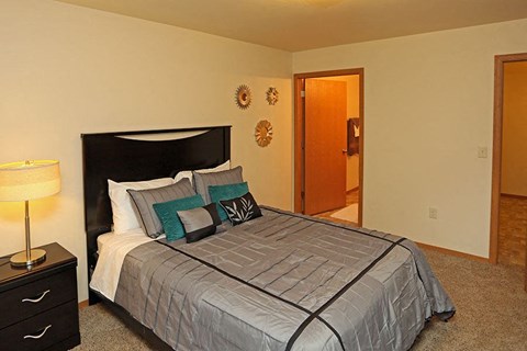 A bedroom with a bed, nightstand, and two wall decorations.