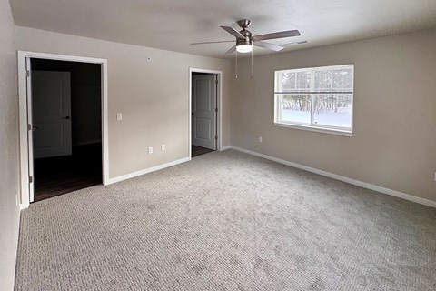 A room with a ceiling fan and carpeted floor.