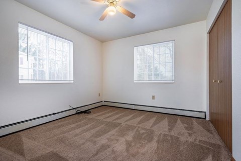 A room with a carpeted floor and a ceiling fan.