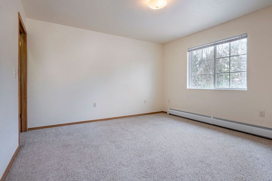 A room with a carpeted floor and a window.