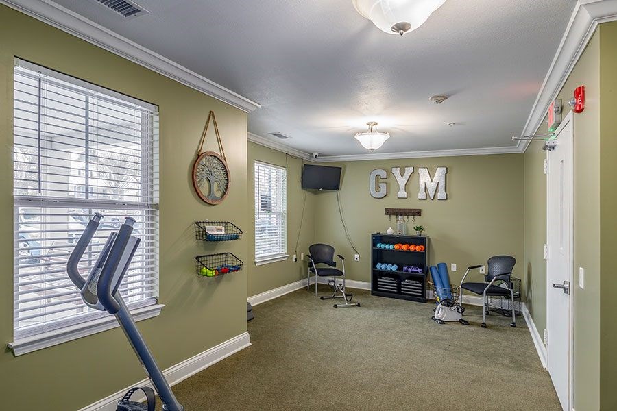 A gym room with a treadmill, exercise equipment, and a flat screen TV.