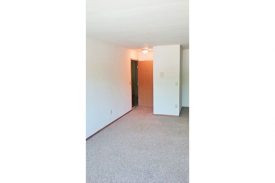 an empty living room with a white wall and carpet