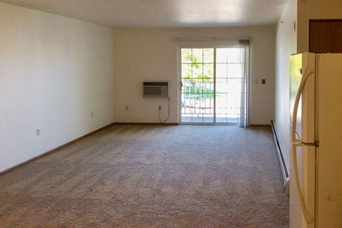 an empty living room with a refrigerator and a door