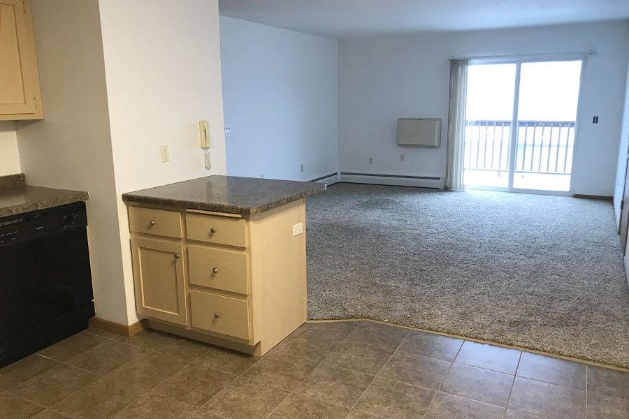 an empty kitchen and living room with a counter in the middle