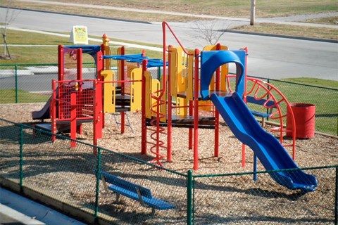 A playground with a blue slide and red and yellow play structures.