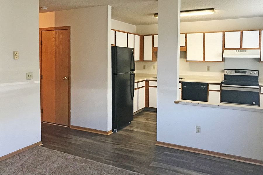 an empty kitchen with a black refrigerator and