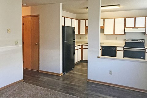 an empty kitchen with a black refrigerator and