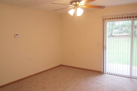 an empty living room with a ceiling fan and a window