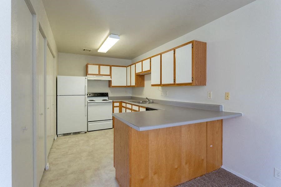 an empty kitchen with an island and white appliances