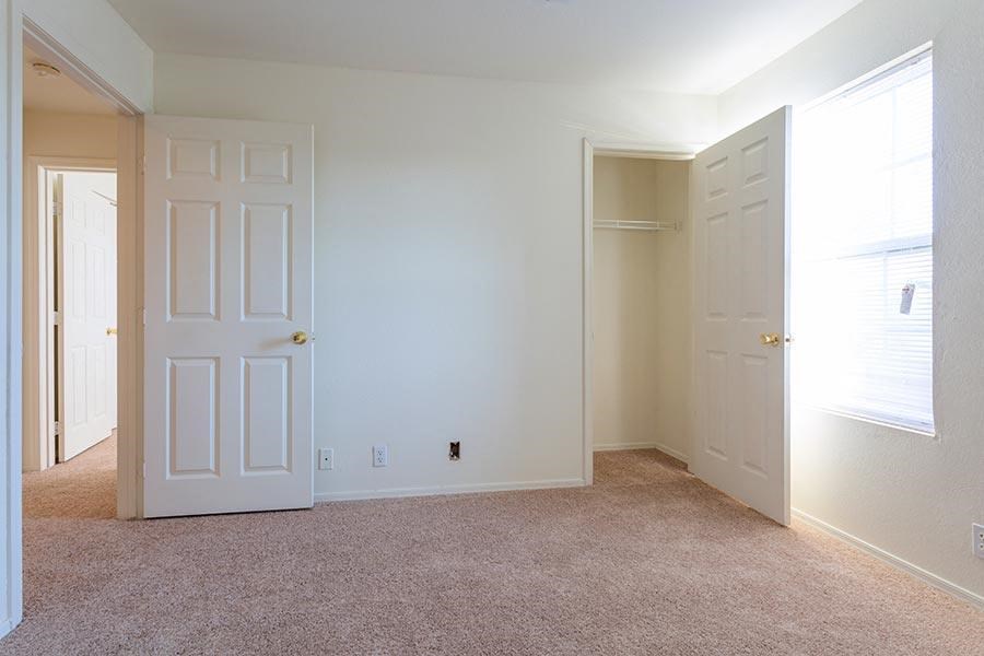 an empty room with a white door and a closet