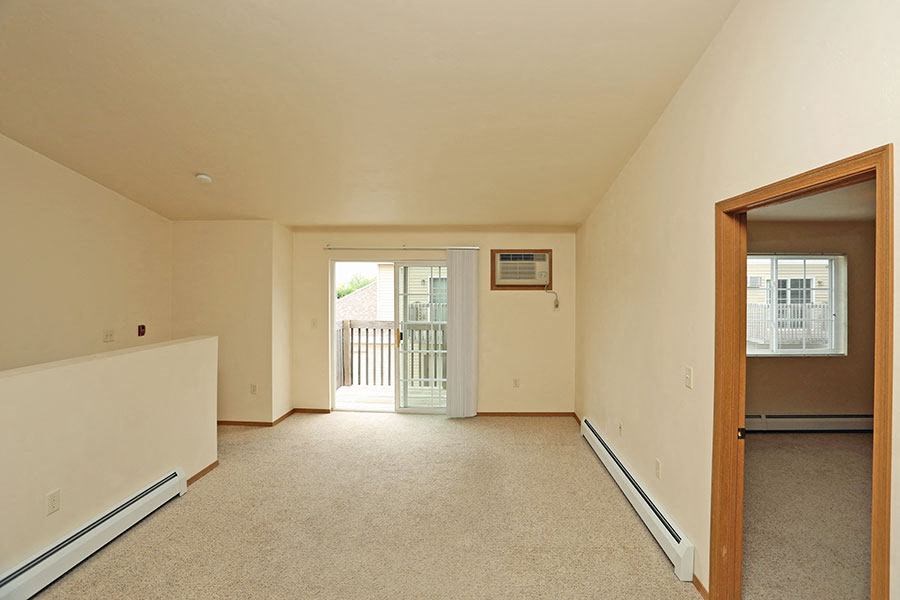 an empty living room with a door to a balcony