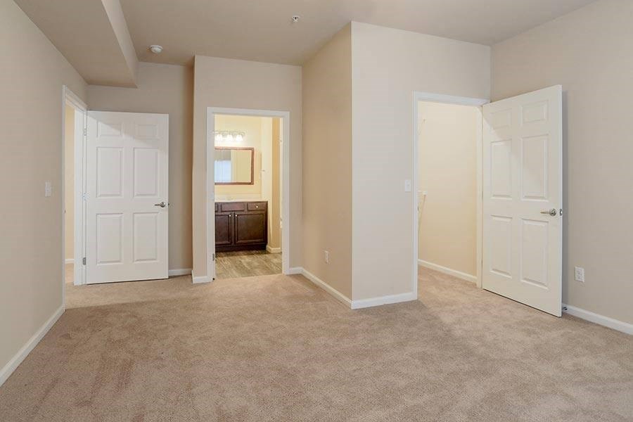 an empty living room with two doors and a bathroom