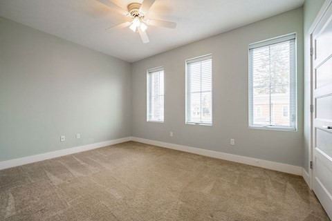 A room with a ceiling fan and carpeted floor.