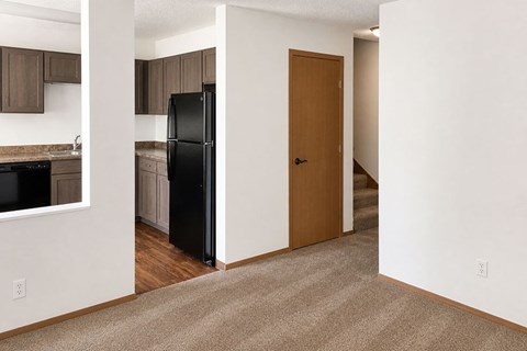 A black refrigerator is in a kitchen with brown cabinets.