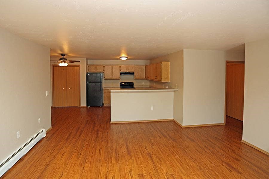 an empty living room and kitchen with a wood floor