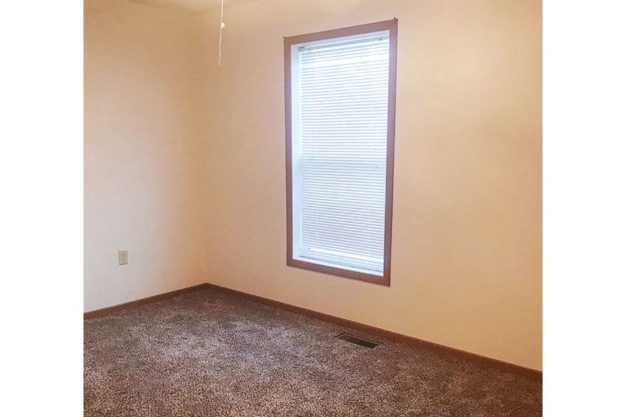 an empty room with a window and a carpet