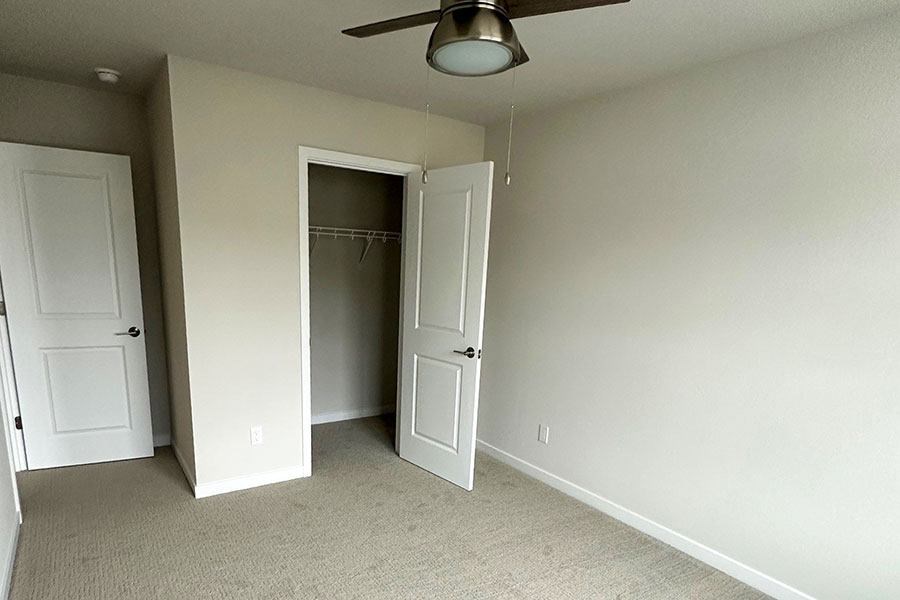 A room with a ceiling fan and two doors.