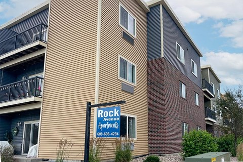 A sign for Rock Avenue Apartments is in front of a building.