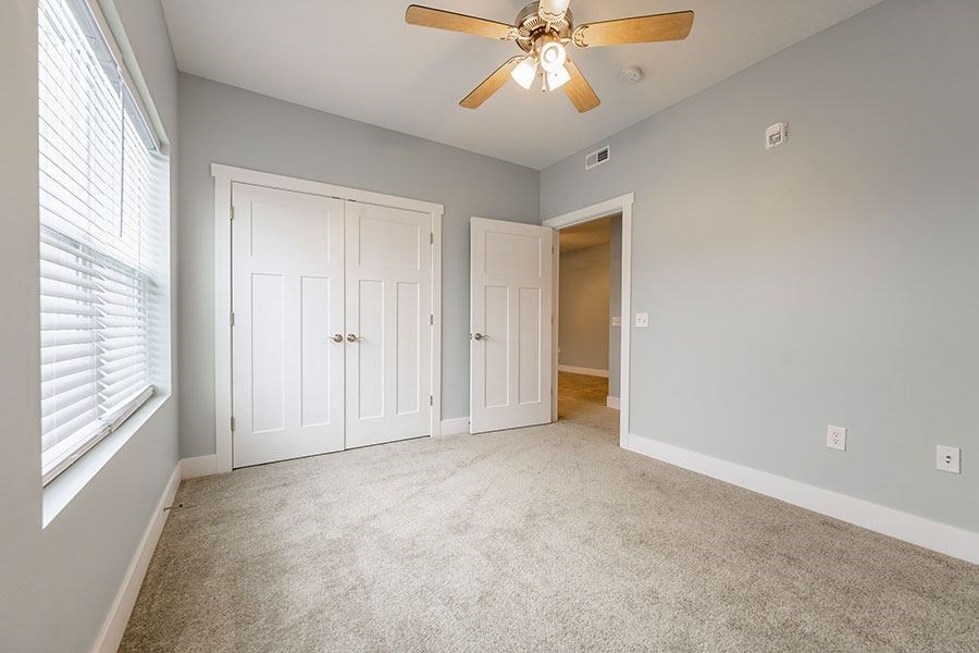 A room with a ceiling fan and two doors.