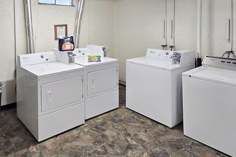 A white washing machine and dryer are in a room with a tiled floor.