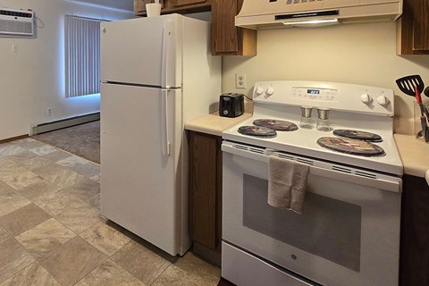 A white refrigerator stands next to a white stove in a kitchen.