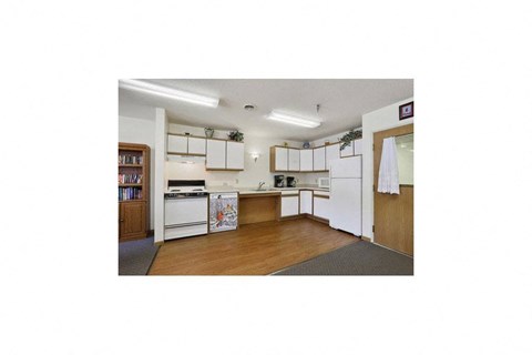 a kitchen with white appliances and a wooden floor