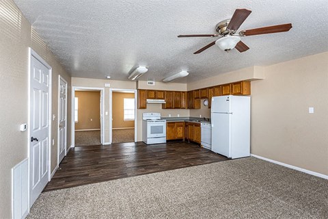 an empty kitchen with white appliances and a ceiling fan