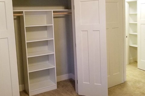 A white shelving unit with multiple shelves is open in a room.