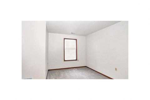 A room with a window and a white wall.